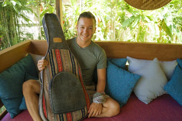 Jovem bonito e feliz misto etnia homem em estilo hipster arrepiante ao ar livre com guitarra relaxado no tranquilo jardim tropical desfrutando de férias retiro — Fotografia de Stock