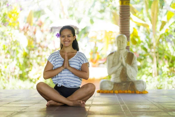Junge schöne und glückliche asiatische indonesische Frau mit balinesischen Stil Ohrblume sitzt auf Holzboden in Lotus posieren lächelnd im Yoga-Studio entspannt und Zen wie in Harmonie — Stockfoto