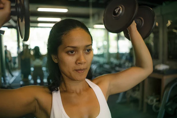 Γυμναστήριο club lifestyle πορτρέτο των νέων ελκυστική και ευτυχισμένη αθλητική ασιατική ινδονησιακή γυναίκα κατάρτισης στο γυμναστήριο άρση βαρών αλτήρες ιδρωμένος και αποφασισμένος — Φωτογραφία Αρχείου