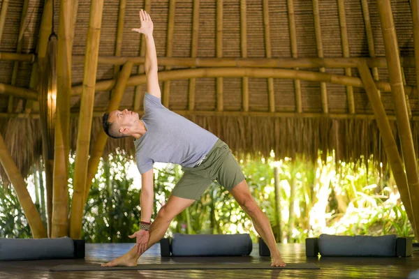 Giovane uomo attraente e felice facendo esercitazione yoga ed esercizio di equilibrio rilassato in armonia a bella capanna di bambù asiatico godendo la natura nel corpo e l'equilibrio della mente — Foto Stock