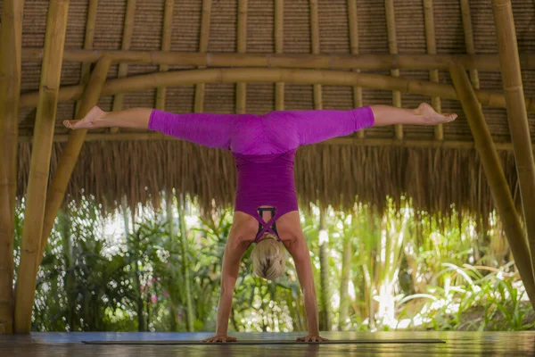 Giovane donna americana felice e bella bionda che fa allenamento di yoga a Bali in capanna di bambù esotico aperto alla foresta in forma fisica e stile di vita sano godendo ritiro — Foto Stock