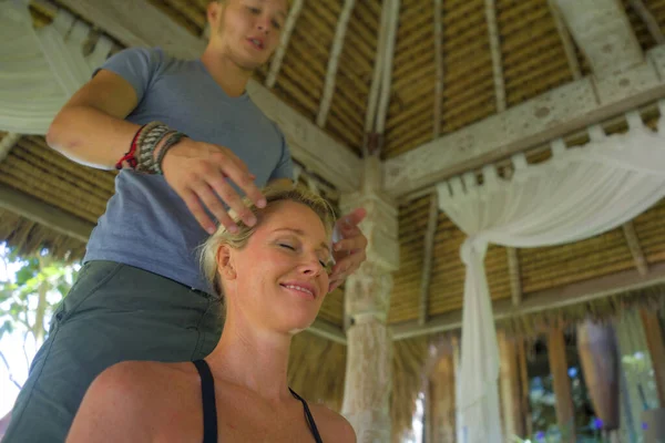 Nahaufnahme Masseur Hände und Gesicht der jungen schönen und glücklichen amerikanischen Touristin mit traditioneller Massage im asiatischen Outdoor-Spa genießen Urlaub Rückzug — Stockfoto