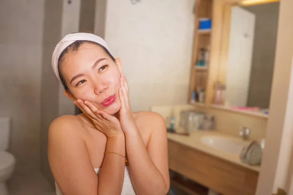 Portrait de style de vie domestique de jeune belle et heureuse femme chinoise asiatique appliquant visage crème cosmétique souriant gai au miroir de salle de bains dans les soins de la peau beauté — Photo