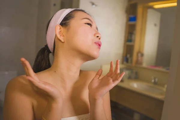 Portrait de style de vie domestique de jeune belle et heureuse femme asiatique coréenne appliquant la crème cosmétique faciale souriant gai au miroir de salle de bains dans les soins de la peau beauté — Photo