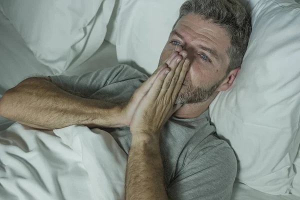 Dramatic portrait of stressed and frustrated man in bed awake at night suffering insomnia sleeping disorder tired and desperate unable sleep feeling exhausted — Stock Photo, Image
