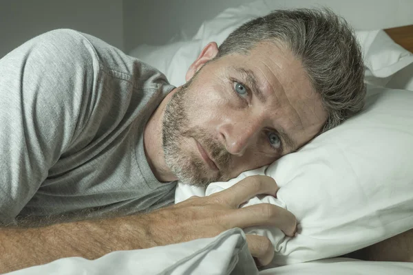 Retrato dramático de homem estressado e frustrado na cama acordado à noite sofrendo insônia distúrbio do sono cansado e desesperado incapazes de dormir sentindo-se exausto — Fotografia de Stock