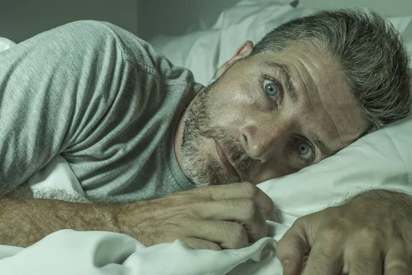 Dramático retrato del hombre estresado y frustrado en la cama despierto por la noche que sufre de insomnio trastorno del sueño cansado y desesperado incapaz de dormir sensación agotada —  Fotos de Stock