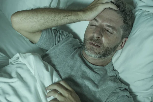 Retrato dramático de homem estressado e frustrado na cama acordado à noite sofrendo insônia distúrbio do sono cansado e desesperado incapazes de dormir sentindo-se exausto — Fotografia de Stock