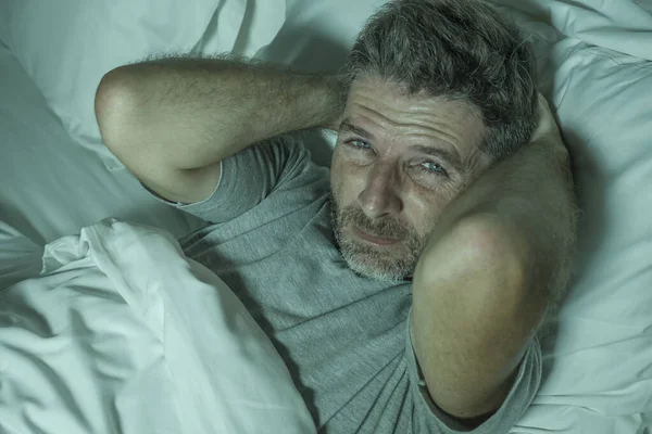 Dramático retrato del hombre estresado y frustrado en la cama despierto por la noche que sufre de insomnio trastorno del sueño cansado y desesperado incapaz de dormir sensación agotada — Foto de Stock