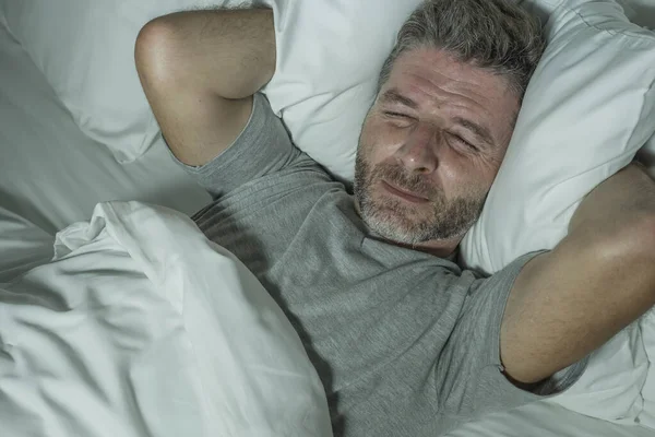 Retrato dramático de homem estressado e frustrado na cama acordado à noite sofrendo insônia distúrbio do sono cansado e desesperado incapazes de dormir sentindo-se exausto — Fotografia de Stock