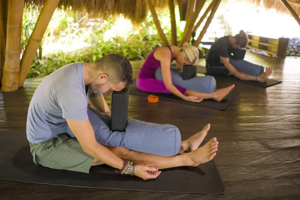 Yogastunde im Freien - Gruppe junger Leute und Trainerin üben gemeinsam Entspannungsübungen in asiatischer Wellness-Schutzhütte, um Körper und Geist im Gleichgewicht zu halten — Stockfoto