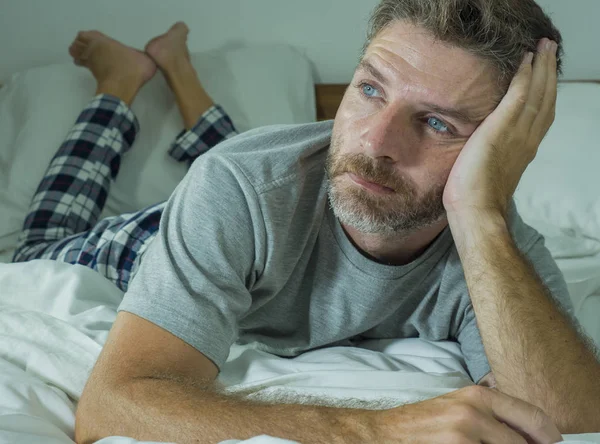 Young sad and depressed man lying thoughtful and pensive on bed looking away feeling lost thinking suffering some problem in sadness emotion and depression concept — Stock Photo, Image