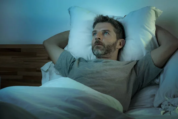 Young sad and depressed man lying thoughtful and pensive on bed looking away feeling lost thinking suffering some problem in sadness emotion and depression concept — Stock Photo, Image