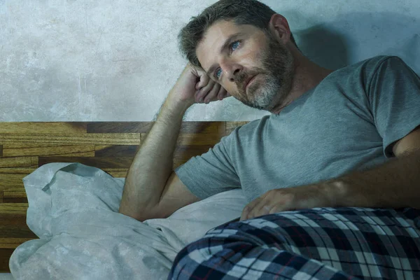 Młody smutny i przygnębiony mężczyzna leżący przemyślany i zamyślony na łóżku odwracając wzrok czując się zagubionym myśląc cierpiąc jakiś problem w smutku emocji i koncepcji depresji — Zdjęcie stockowe