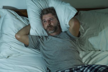 Genç, çekici, üzgün ve depresif bir adamın dramatik yaşam tarzı portresi. Geceleri yatağa uzanmış. Stresli ve çaresiz hissediyor.