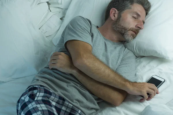 Stile di vita domestico ritratto ad alto angolo di giovane uomo attraente e stanco che dorme sul letto con telefono cellulare in internet e dipendenza dai social media e uso eccessivo della rete — Foto Stock