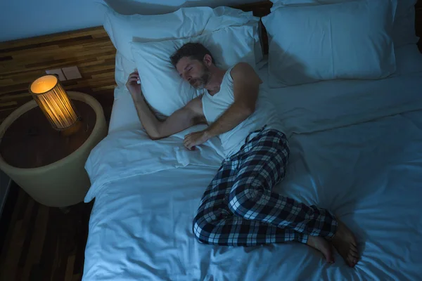 Estilo de vida doméstico retrato de alto ângulo de homem jovem atraente e relaxado dormindo sozinho na cama em casa deitado tranquilo à noite em pouca luz descansando e sonhando — Fotografia de Stock