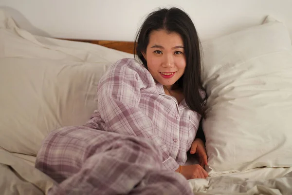 Lifestyle Porträt einer jungen schönen und süßen asiatischen Chinesin im Bett, die sich glücklich und entspannt fühlt und süße Pyjamas trägt und den faulen Sonntagmorgen zu Hause genießt — Stockfoto