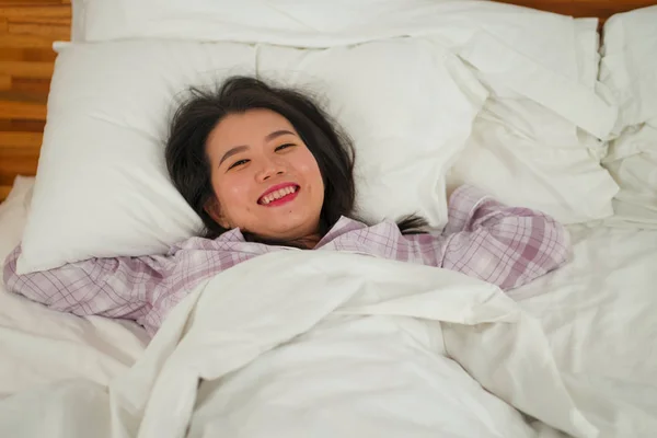 Lifestyle Porträt einer jungen schönen und süßen asiatischen Chinesin im Bett, die sich glücklich und entspannt fühlt und süße Pyjamas trägt und den faulen Sonntagmorgen zu Hause genießt — Stockfoto