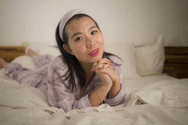 Lifestyle Porträt einer jungen schönen und süßen asiatischen Chinesin im Bett, die sich glücklich und entspannt fühlt und süße Pyjamas trägt und den faulen Sonntagmorgen zu Hause genießt — Stockfoto