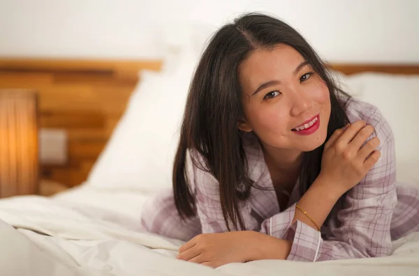 Образ жизни портрет молодой красивой и сладкой азиатской китаянки в постели, чувствуя себя счастливым и расслабленным носить милые пижамы наслаждаясь ленивым воскресным утром дома — стоковое фото