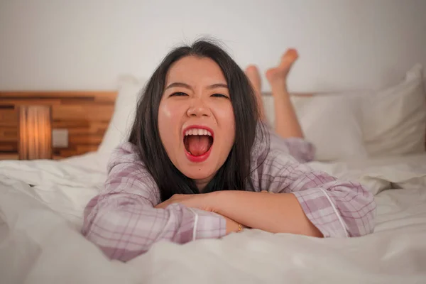 Портрет життя молодої красивої і солодкої азіатської китайки в ліжку відчуває себе щасливою і розслабленою, одягненої в милу піжаму, яка насолоджується лінивою неділею вранці вдома. — стокове фото