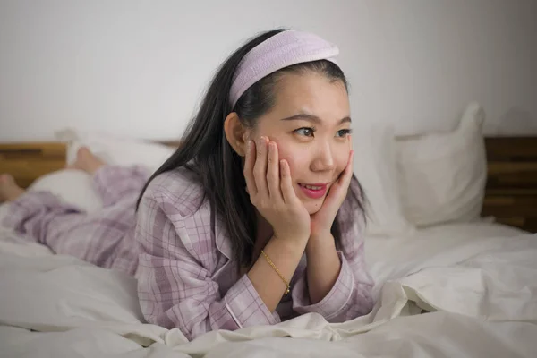 Lifestyle Porträt einer jungen schönen und süßen asiatischen Chinesin im Bett, die sich glücklich und entspannt fühlt und süße Pyjamas trägt und den faulen Sonntagmorgen zu Hause genießt — Stockfoto