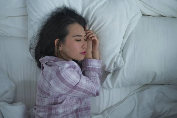 Портрет життя молодої красивої і солодкої азіатської корейської дівчини на самоті, яка спить спокійно в піжамі, лежачи на ліжку щасливо і зручно відпочиваючи. — стокове фото