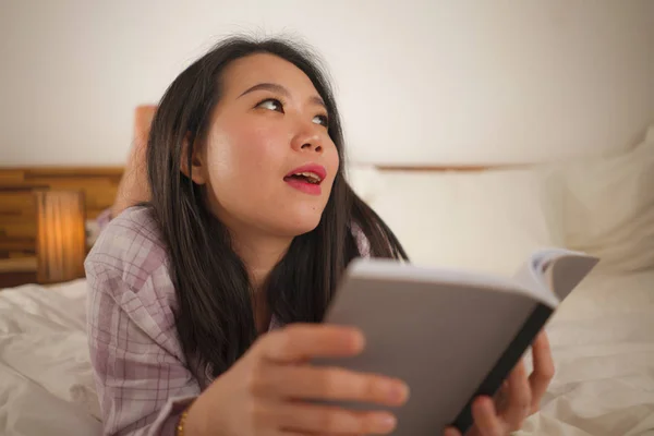 Jeune belle et douce Asiatique chinois femme au lit lecture livre roman se sentir heureux et détendu ou étudier à la maison en pyjama mignon regardant confortable et accueillant — Photo