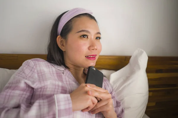 Junge schöne und süße asiatische Chinesin im niedlichen Schlafanzug verspielt im Bett mit dem Handy genießen soziale Medien oder Online-Dating-App glücklich und entspannt — Stockfoto