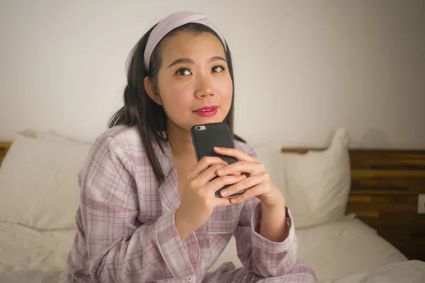 Junge schöne und süße asiatische Chinesin im niedlichen Schlafanzug verspielt im Bett mit dem Handy genießen soziale Medien oder Online-Dating-App glücklich und entspannt — Stockfoto