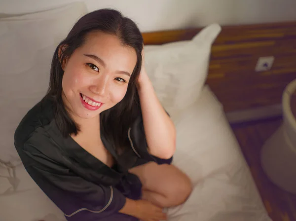 Genç, güzel ve tatlı Asyalı Koreli kadın kendini mutlu ve rahat hissediyor. Hoş bir gecelik giyiyor ve evde tembelce pazar sabahının keyfini çıkarıyor. — Stok fotoğraf