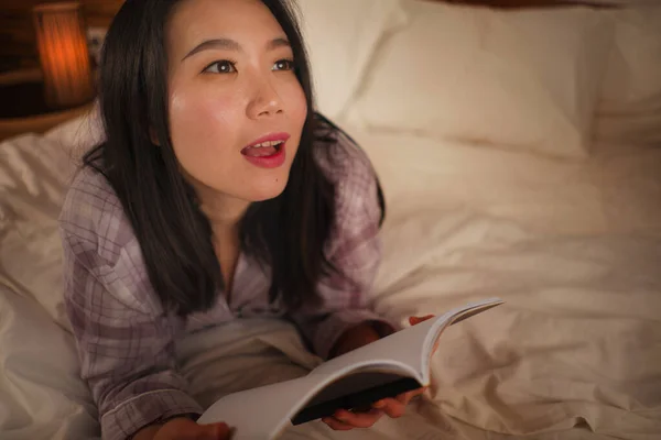 Junge schöne und süße asiatische Chinesin im Bett liest Buch Roman glücklich und verspielt fühlen oder zu Hause studieren in niedlichen Pyjama sieht gemütlich und heimelig — Stockfoto