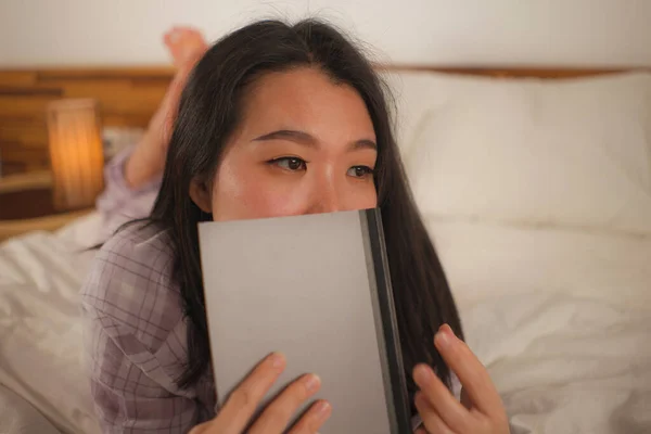 Junge schöne und süße asiatische Chinesin im Bett liest Buch Roman glücklich und verspielt fühlen oder zu Hause studieren in niedlichen Pyjama sieht gemütlich und heimelig — Stockfoto