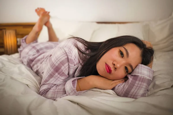 Lifestyle πορτρέτο της νεαρής όμορφης και γλυκιάς Κορεάτισσας στο κρεβάτι που αισθάνεται ευτυχισμένη και χαλαρή φορώντας χαριτωμένες πιτζάμες απολαμβάνοντας τεμπέλης Κυριακή πρωί στο σπίτι — Φωτογραφία Αρχείου