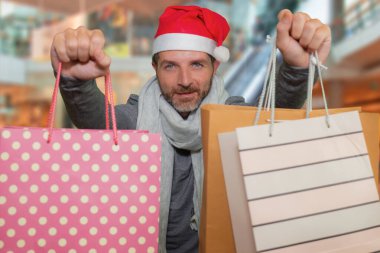 Noel Baba şapkalı ve eşarplı genç ve çekici hippi elinde bir sürü alışveriş çantasıyla alışveriş merkezinde heyecanlı ve neşeli hediyeler alıyor.