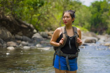 Genç, güzel ve mutlu Asyalı Çinli kadın sırt çantasıyla dağları aşıyor. Nehrin karşısına geçiyor. Tatilin tadını çıkarıyor. 