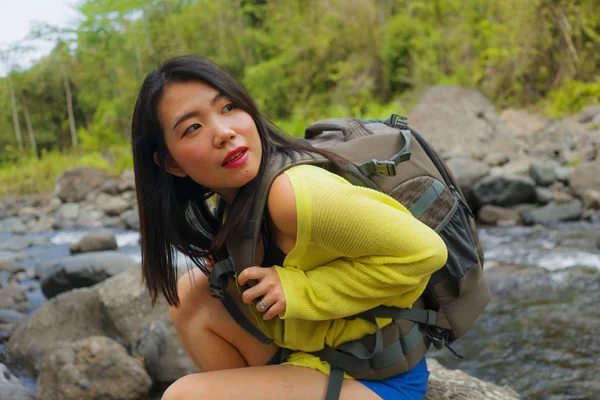 아름답고 행복 한 젊은 아시아인 여자가 여행 가방을 들고 강을 건너는 산위를 걷고 있다. — 스톡 사진