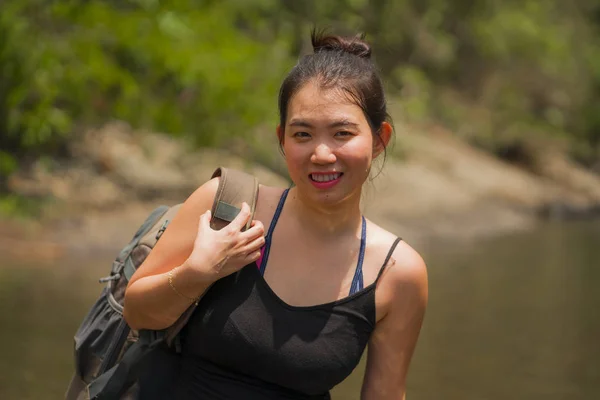 강을 건너는 산에서 배낭을 메고 강을 건너며 휴가를 즐기며 신선 한 환경을 즐기고 있는 젊고 아름답고 행복 한 아시아인 여성의 사진 이 실외에 있다 — 스톡 사진