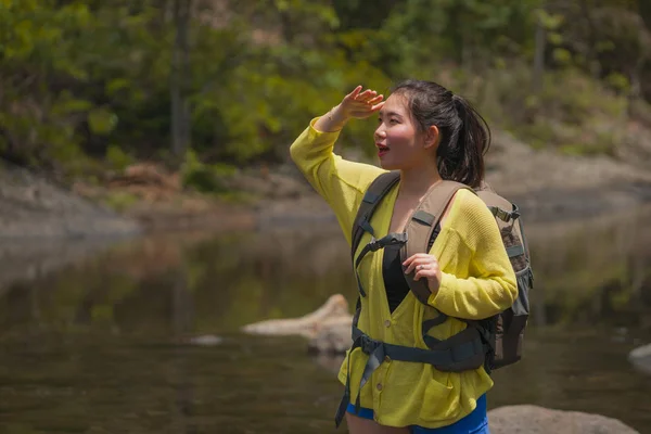 Νεαρή όμορφη και ευτυχισμένη ασιατική ιαπωνική γυναίκα μεταφέρουν σακίδιο πεζοπορία στα βουνά διασχίζοντας ποτάμι απολαμβάνοντας φύση διακοπών και φρέσκο περιβάλλον πεζοπορία χαρούμενα — Φωτογραφία Αρχείου