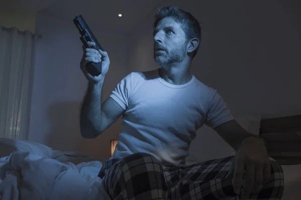 스트레스받고 편집증에 시달리는 미국 남자가 침대에 앉아 총을 들고 잠을 이룰 수없었다. — 스톡 사진