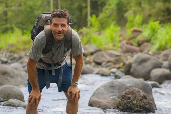 Joven hombre feliz y atractivo con viaje mochila senderismo en el río en el bosque sintiéndose libre disfrutando de la naturaleza y el ambiente fresco en el viaje de senderismo de verano — Foto de Stock