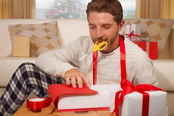 Natale vacanza stile di vita ritratto di giovane uomo attraente e felice a casa preparare regali di Natale avvolgente regali e scatole con carta e nastro sorridente allegro — Foto Stock