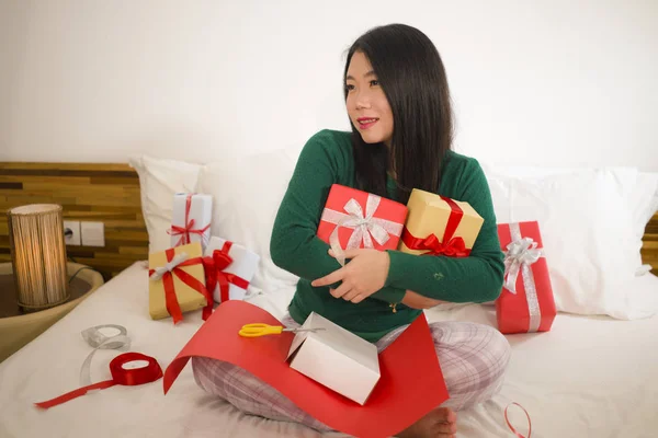 Χριστουγεννιάτικο πορτρέτο του τρόπου ζωής των διακοπών των νέων ευτυχισμένη και γλυκιά ασιατική κινεζική γυναίκα κάθεται στο κρεβάτι προετοιμασία Χριστούγεννα παρουσιάζει συσκευασία κουτιά δώρων και προσθέτοντας κορδέλες — Φωτογραφία Αρχείου