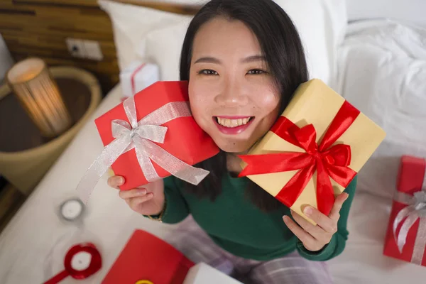 Χριστουγεννιάτικο πορτρέτο του τρόπου ζωής των διακοπών των νέων ευτυχισμένη και γλυκιά ασιατική ιαπωνική γυναίκα κάθεται στο κρεβάτι προετοιμασία Χριστούγεννα παρουσιάζει συσκευασία κουτιά δώρων και προσθέτοντας κορδέλες — Φωτογραφία Αρχείου