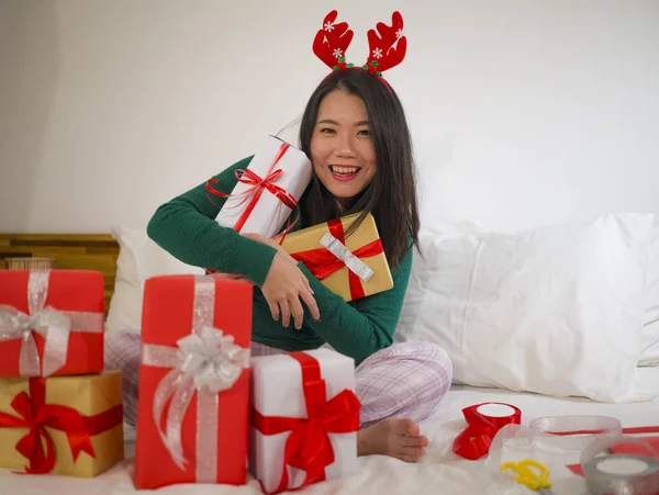 Χριστουγεννιάτικο πορτρέτο του τρόπου ζωής των διακοπών των νέων ευτυχισμένη και όμορφη ασιατική κορεάτισσα γυναίκα στο κρεβάτι σε γλυκά κέρατα ταράνδων προετοιμασία Χριστούγεννα παρουσιάζει συσκευασία κουτιά δώρων απολαμβάνοντας — Φωτογραφία Αρχείου