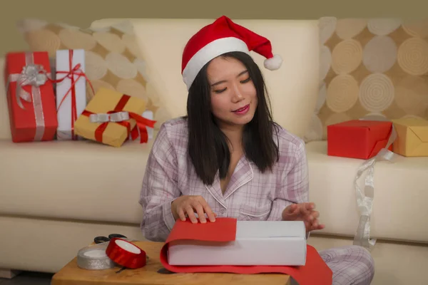 Χριστουγεννιάτικο πορτρέτο lifestyle διακοπές των νέων όμορφη και ευτυχισμένη ασιατική κορεάτισσα γυναίκα σε Σάντα καπέλο ενθουσιασμένοι περιτύλιγμα Χριστούγεννα δώρα συσκευασίας με χαρτί και ταινία — Φωτογραφία Αρχείου
