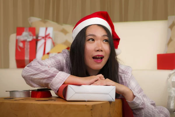 Χριστουγεννιάτικο πορτρέτο lifestyle διακοπές των νέων όμορφη και ευτυχισμένη ασιατική κορεάτισσα γυναίκα σε Σάντα καπέλο ενθουσιασμένοι περιτύλιγμα Χριστούγεννα δώρα συσκευασίας με χαρτί και ταινία — Φωτογραφία Αρχείου