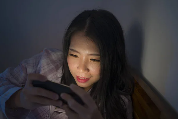 Fiatal szép és boldog édes ázsiai koreai nő pizsamában élvezi a mobiltelefon app az ágyban éjszaka a közösségi média függőség koncepció — Stock Fotó