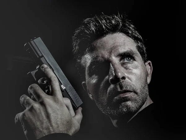 Nahaufnahme Portrait von ernsthaften und attraktiven Hitman oder Special Agent Mann hält Waffe isoliert auf schwarzem Hintergrund in Geheimdienst-Hollywood-Stil Film und filmische Beleuchtung — Stockfoto